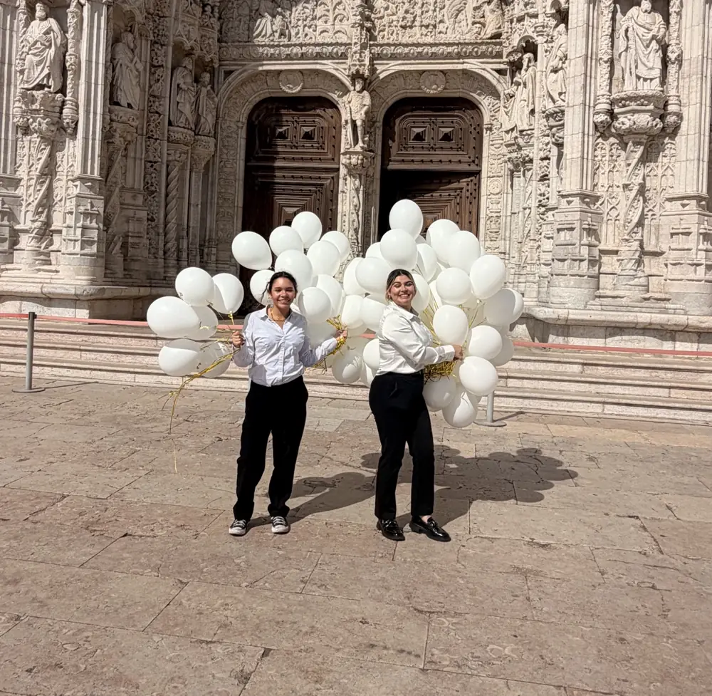 Duas hospedeiras da Prime Corporate Solutions com balões brancos à porta do Mosteiro dos Jerónimos, em Lisboa